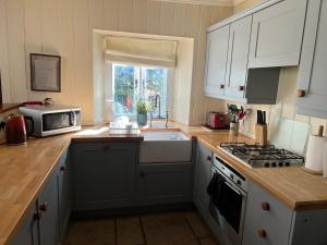 a kitchen with white cabinets and a microwave at Cosy Cottage Overlooking Malmesbury Abbey in Malmesbury +24 photos