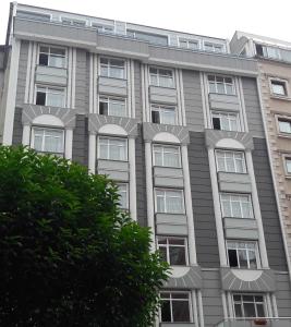 un bâtiment gris avec des fenêtres blanches et un arbre dans l'établissement Sumela Park Hotel, à Trabzon