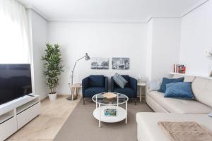 a white living room with a white couch and blue chairs at The Lucky Flats - Pintor Sorolla in Alicante