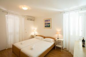 a bedroom with a bed and two tables and two windows at Central Apartment in Dubrovnik +17 photos
