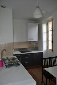 une cuisine avec des armoires en noir et blanc et une table dans l'établissement Les Charmottes, à Nuits-Saint-Georges
