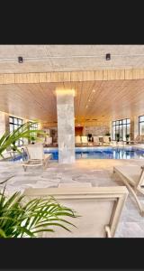 una grande piscina con sedie e una piscina di Alezzi Odyssey Luxury Pool Spa a Mamaia Nord - Năvodari