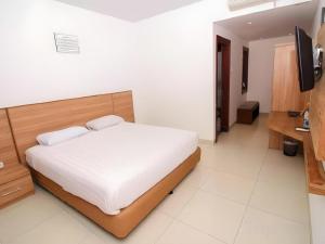 a bedroom with a bed and a flat screen tv at Hotel Adilla Syariah Ambarukmo in Yogyakarta