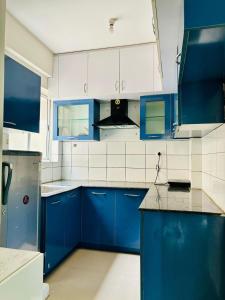 a blue and white kitchen with blue cabinets at Home Stay 1 BHK Apartment Electronic City -Oakwood in Attibele