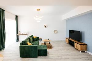 a living room with a green couch and a tv at Premium Tulip Aparthotel close to Airport & Therme in Tunari