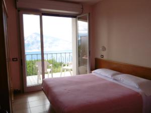 a bedroom with a bed with a view of a balcony at Hotel Miralago in San Zeno di Montagna