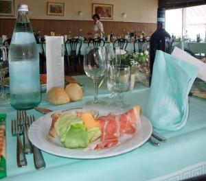 einen Tisch mit einem Teller Essen und einer Flasche Wein in der Unterkunft Hotel Miralago in San Zeno di Montagna