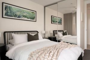 Un dormitorio con dos camas y un gran espejo. en Terra Suite - Central Dunsborough Luxury Apartment, en Dunsborough
