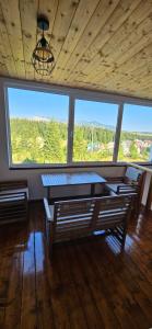 a room with a table and two benches and windows at Durmitor Panorama Lodge in Junčev Do
