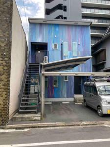un edificio azul con una escalera en un aparcamiento en Lhouseー遊べる宿ビリヤード 大型スクリーン 岡山駅徒歩15分, en Okayama