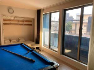 una mesa de billar en una habitación con una ventana grande en Lhouseー遊べる宿ビリヤード 大型スクリーン 岡山駅徒歩15分, en Okayama