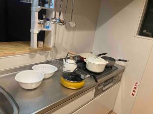 cocina con ollas y sartenes en una estufa en Lhouseー遊べる宿ビリヤード 大型スクリーン 岡山駅徒歩15分, en Okayama 40 fotos más