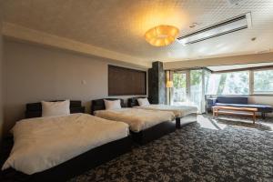 a hotel room with two beds and a couch at Atami Season Hotel in Atami