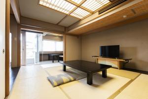 a living room with a table and a tv at Atami Season Hotel in Atami