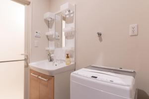 a white bathroom with a sink and a washing machine at BON Osaka Namba East in Osaka