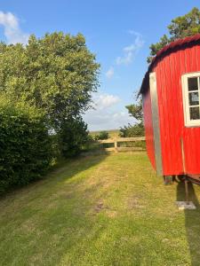 a red train car sitting in a grass field at Bauwagen in Fanø
