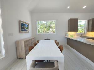 a white kitchen with a white table and chairs at Silver Palms - Brand New Designer Home on Banks Road home in North Palmetto Point