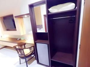 Cette chambre comprend un bureau et une armoire avec un miroir. dans l'établissement Hotel Khalista, à Gurungsang