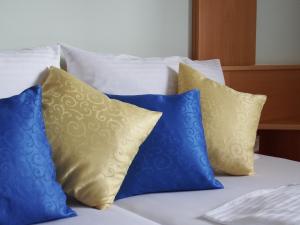 4 almohadas azules y amarillas en una cama en Gartenpension Fischl, en Mörbisch am See
