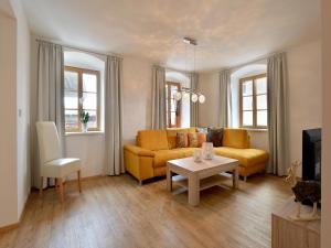 een woonkamer met een gele bank en een tafel bij Jägerhaus Apartment near ski area in Hopfgarten im Brixental