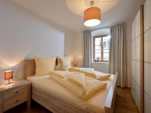 een slaapkamer met een bed met witte lakens en een raam bij Jägerhaus Apartment near ski area in Hopfgarten im Brixental