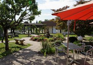 a patio with an umbrella and a table and chairs at Charme Hôtel, Montbéliard Sud in Montbéliard