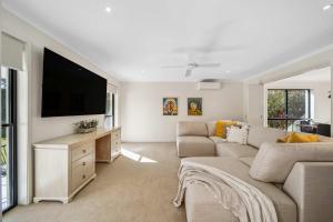 a living room with a couch and a flat screen tv at Mountaintop Pool Retreat - The Ideal Family Escape in Buderim