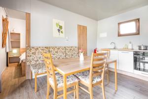 a kitchen and dining room with a wooden table and chairs at Terme Banovci - Mobilne hiške Med Brajdami in Banovci