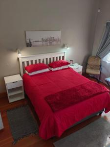 a bedroom with a large red bed with red pillows at Bella & Anastasia in Bloemfontein