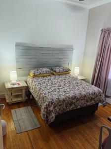 a bedroom with a bed and two tables and two lamps at Bella & Anastasia in Bloemfontein