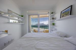a white bedroom with a large bed and a view of the ocean at Luxury Beachfront-LaVista with Mountain & Ocean views in Bloubergstrand