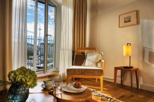 ein Wohnzimmer mit einem Sessel und einem großen Fenster in der Unterkunft Louis Hotel in München