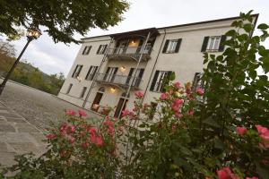 een groot wit gebouw met een balkon en roze rozen bij Villa Durando in Mondovì