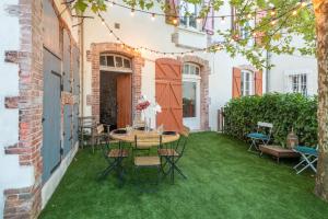 a patio with green grass and a table and chairs at La roche étoilée - Jacuzzi in Vienne