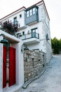 a white house with red doors and a stone wall at Sakula Hotel in Alaçatı