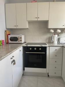 a kitchen with white cabinets and a black oven at Pelagos Hill Apartment in Paphos