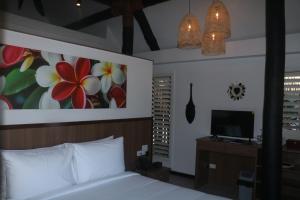 a bedroom with a bed with a painting on the wall at Nawi Island Marina Accommodation in Savusavu