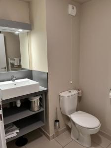 a bathroom with a white toilet and a sink at Agapanthe in Remoulins