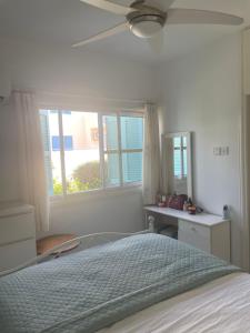 a bedroom with a bed with a ceiling fan and a window at Pelagos Hill Apartment in Paphos