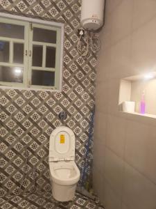 a small bathroom with a toilet and a window at Studio Apartment jungle view 2minutes drive to the beach in Colva