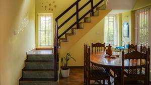 a dining room with a table and a staircase at Willostays Cloudhill ooty in Ooty
