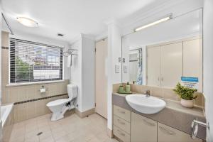 a bathroom with a sink and a toilet and a mirror at Cloud Nine City Centre 1BDR in Perth