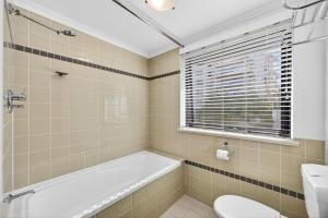 a bathroom with a tub and a toilet and a sink at Cloud Nine City Centre 1BDR in Perth