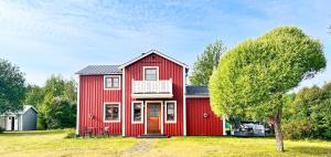 una casa roja con un árbol delante en Cozy Family Villa for aurora lovers, en Byske