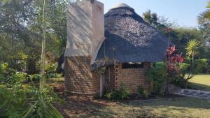Casa pequeña con techo de paja en un jardín en Texas Guesthouse, en Phalaborwa
