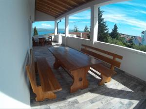 a wooden table and benches on a balcony with a view at Apartments & Rooms Strčić Krk in Krk