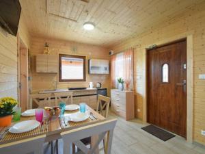 a kitchen with a table and a kitchen with a wooden wall at Domki Pod Brzozami in Sarbinowo