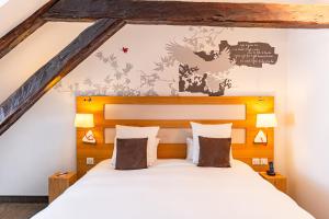 a bedroom with a white bed with a wooden headboard at Le Grand Aigle, Friendly Hotel & Spa in La Salle-les-Alpes