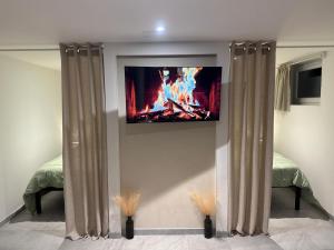 a room with a tv on a wall with curtains at Appartement atypique chaleureux in Rosières-devant-Bar