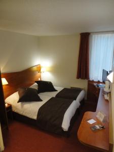Un pat sau paturi într-o cameră la Kyriad Chantilly